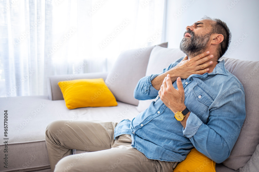 Man Experiencing Throat Pain While Sitting on Couch Man Experiencing Throat Pain While Sitting on Couch