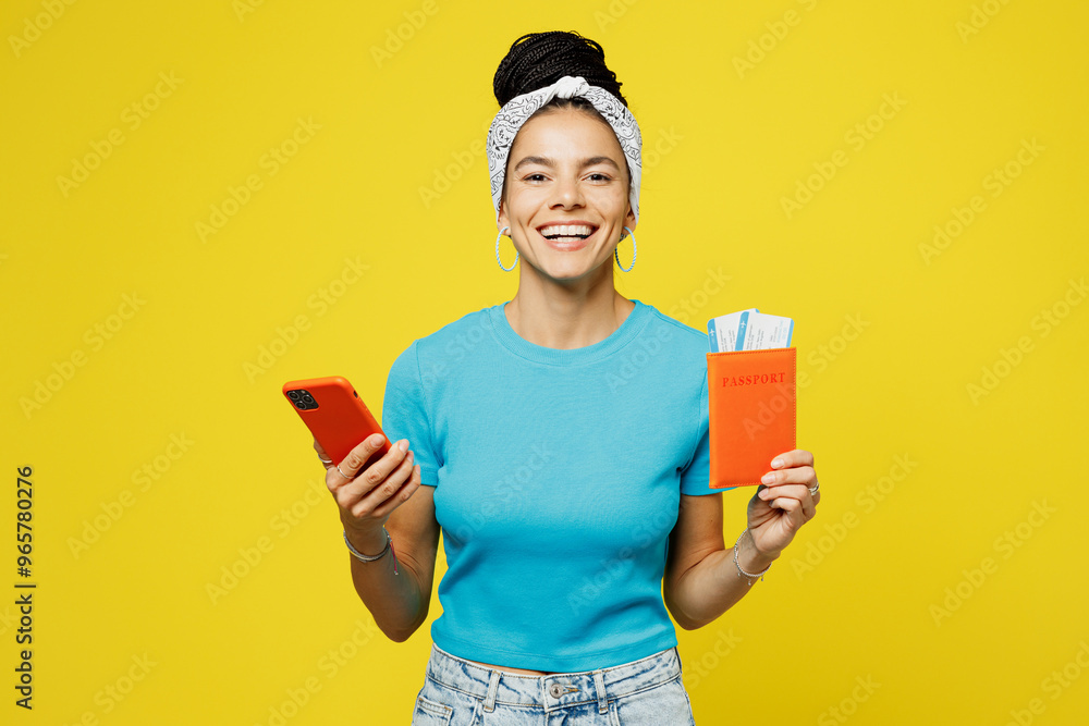 Traveler Latin woman wear blue casual clothes hold passport ticket mobile cell phone isolated on plain yellow background. Tourist travel abroad in free spare time rest getaway Air flight trip concept Traveler Latin woman wear blue casual clothes hold passport ticket mobile cell phone isolated on plain yellow background. Tourist travel abroad in free spare time rest getaway Air flight trip concept