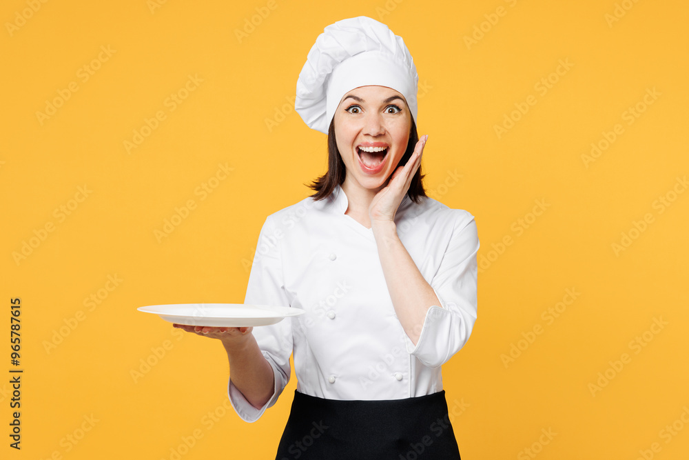 Young shocked chef cook baker woman she wear white shirt black apron uniform toque chefs hat hold in hand empty plate put arm on face isolated on plain yellow background studio. Cooking food concept. Young shocked chef cook baker woman she wear white shirt black apron uniform toque chefs hat hold in hand empty plate put arm on face isolated on plain yellow background studio. Cooking food concept.