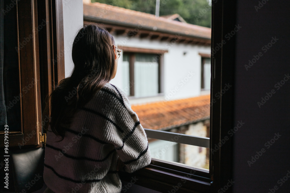 Back view of unrecognizable woman gazing out a window in Asturias Back view of unrecognizable woman gazing out a window in Asturias