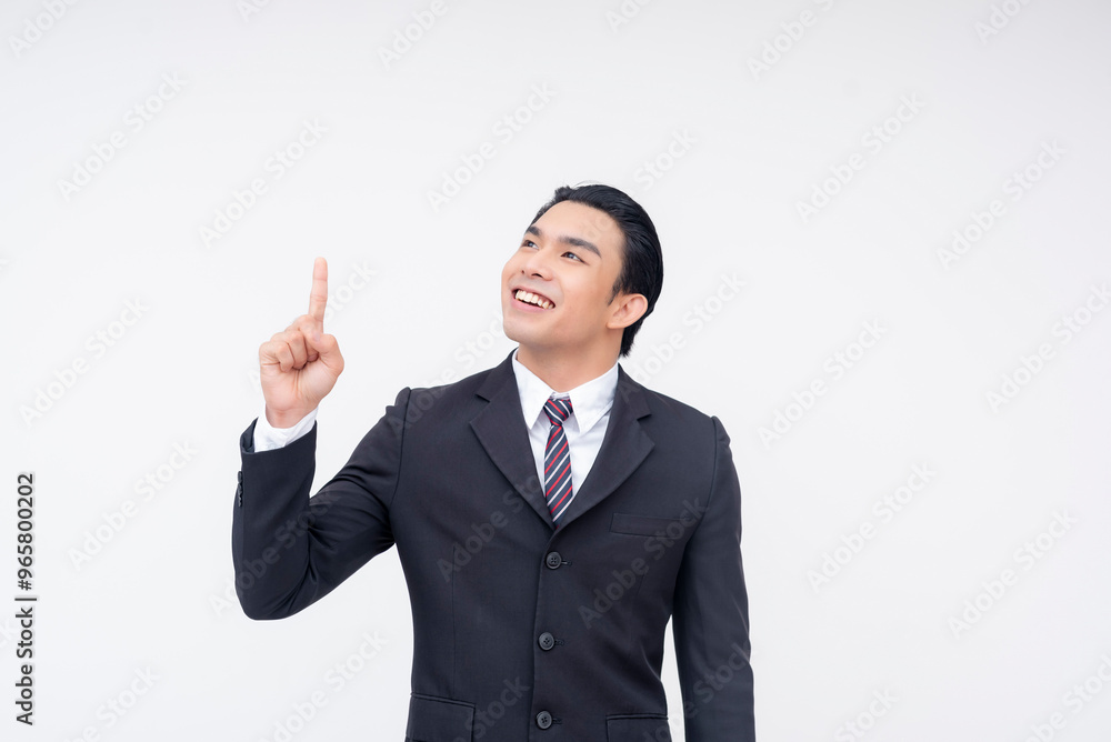 Portrait of an optimistic young asian business executive in a fashionable suit and tie pointing up with his finger. Isolated on a white background. Portrait of an optimistic young asian business executive in a fashionable suit and tie pointing up with his finger. Isolated on a white background.