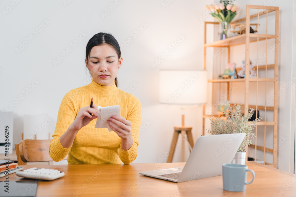 A woman in yellow turtleneck sweater is sitting at wooden desk, writing on notepad. She appears focused and engaged in her work, with laptop and cup of coffee nearby. bright, airy room features lamp a A woman in yellow turtleneck sweater is sitting at wooden desk, writing on notepad. She appears focused and engaged in her work, with laptop and cup of coffee nearby. bright, airy room features lamp a