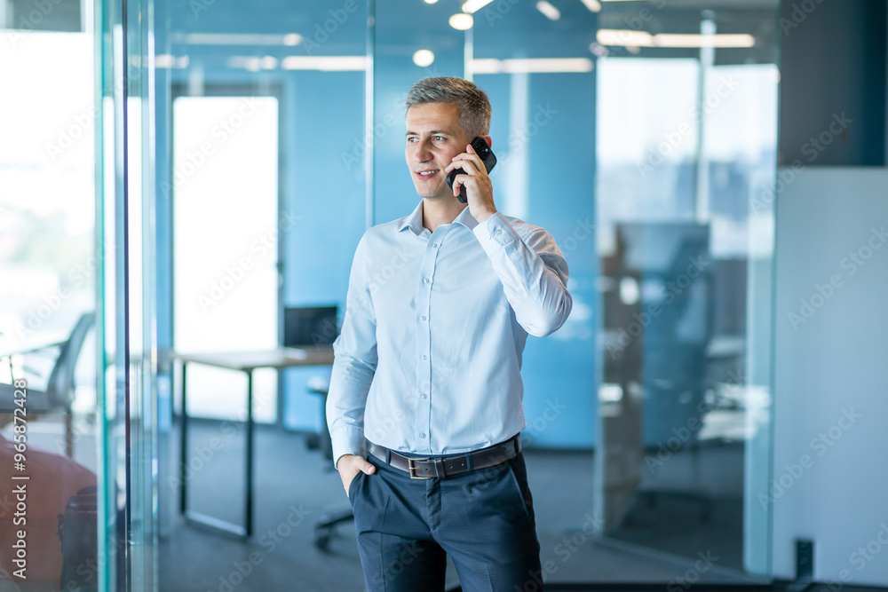 Confident Businessman Talking on Smartphone in Modern Office Confident Businessman Talking on Smartphone in Modern Office