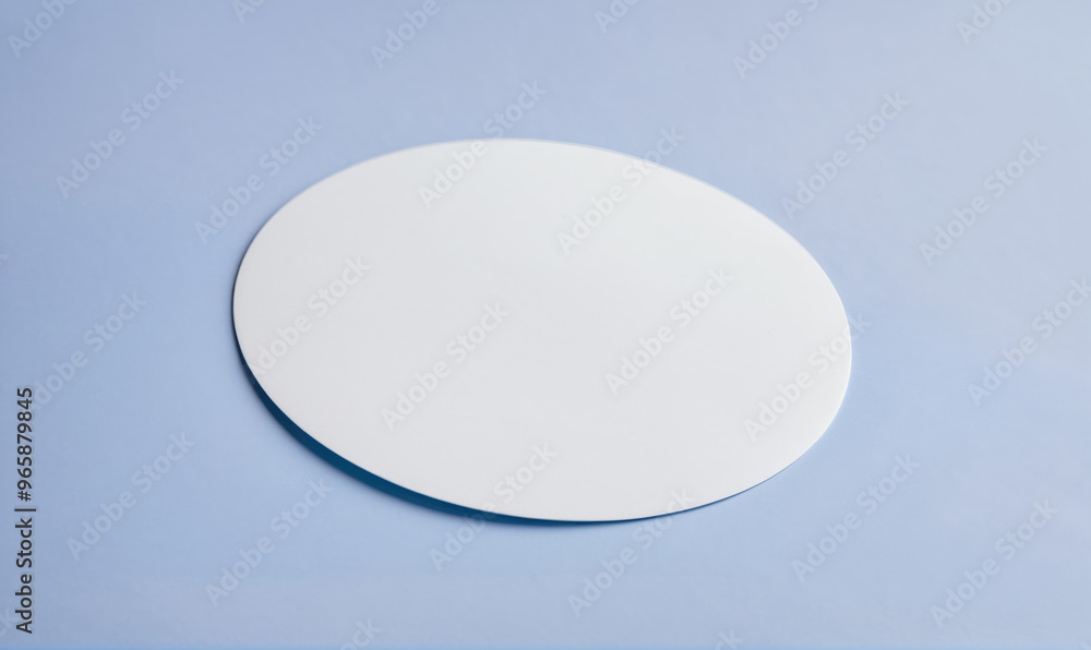A white, round disc sits on a light blue surface A white, round disc sits on a light blue surface