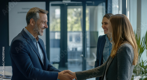 young businesspeople shake hands warmly, sealing a successful business deal during a networking event. The atmosphere is professional.