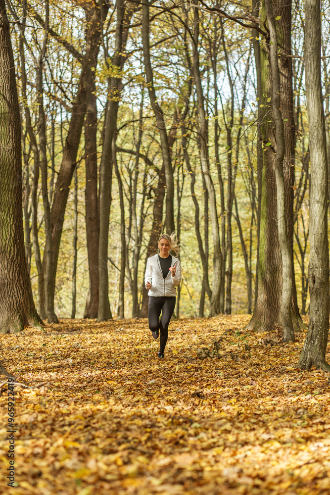 Woman jogging through autumn forest in activewear. Mental health. Woman jogging through autumn forest in activewear. Mental health.