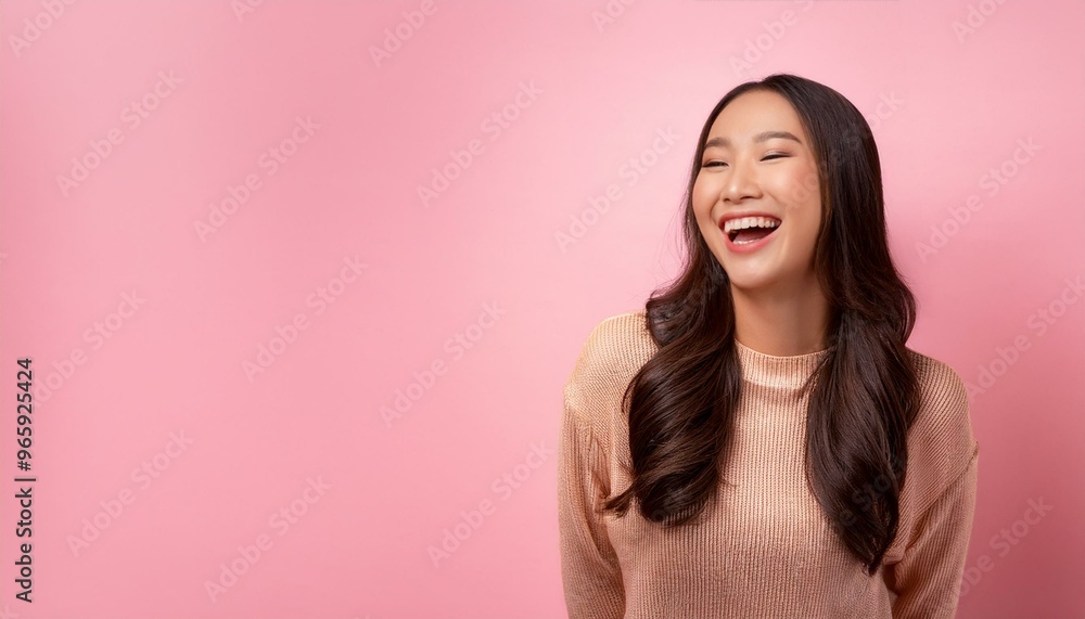 Fototapeta premium Asian woman laughing, Portrait of a beautiful young Asian woman laughing joyfully, isolated on a soft pink background, beauty and radiant smile create a cheerful and uplifting mood, happiness 