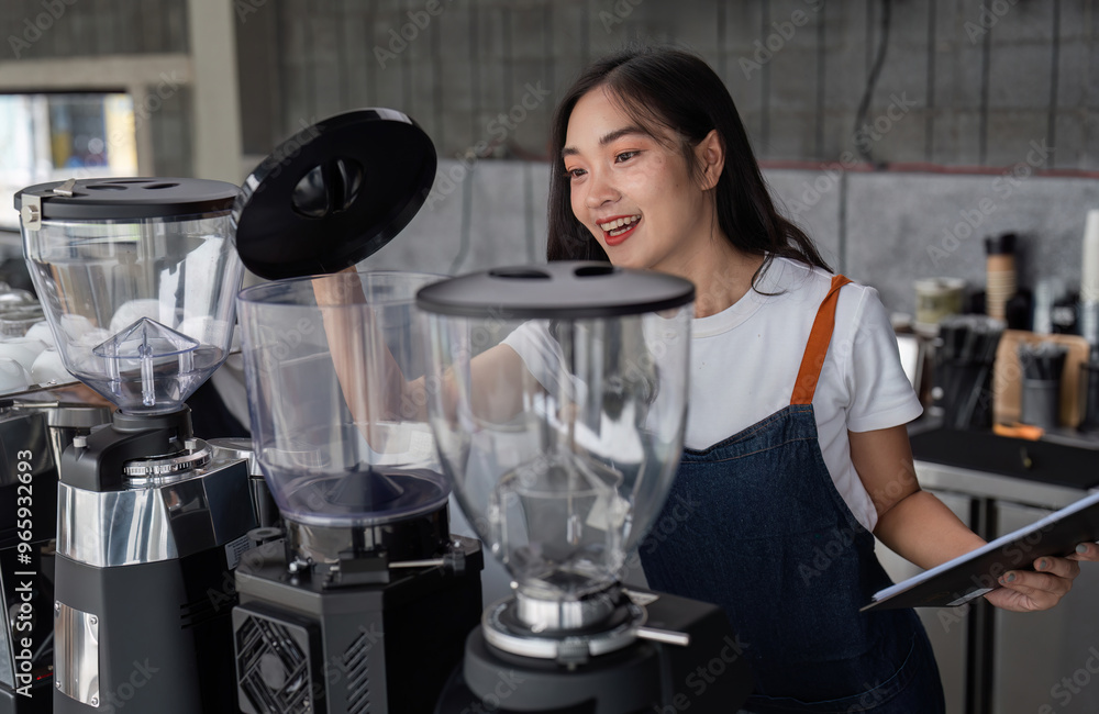 Young Barista Preparing Coffee in a Modern Cafe with a Smile, Wearing Apron and White T-shirt, Operating Coffee Grinder Young Barista Preparing Coffee in a Modern Cafe with a Smile, Wearing Apron and White T-shirt, Operating Coffee Grinder