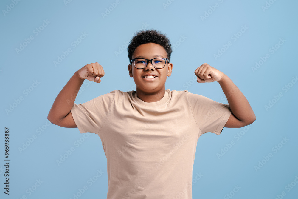 Portrait of strong African teenager wearing yellow t-shirt showing muscles, biceps Portrait of strong African teenager wearing yellow t-shirt showing muscles, biceps
