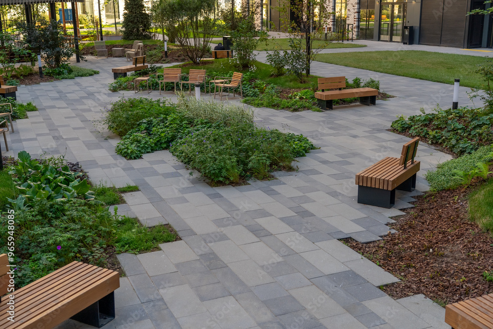 A peaceful garden with wooden benches surrounded by lush plants and pathways in an urban environment on a sunny day A peaceful garden with wooden benches surrounded by lush plants and pathways in an urban environment on a sunny day