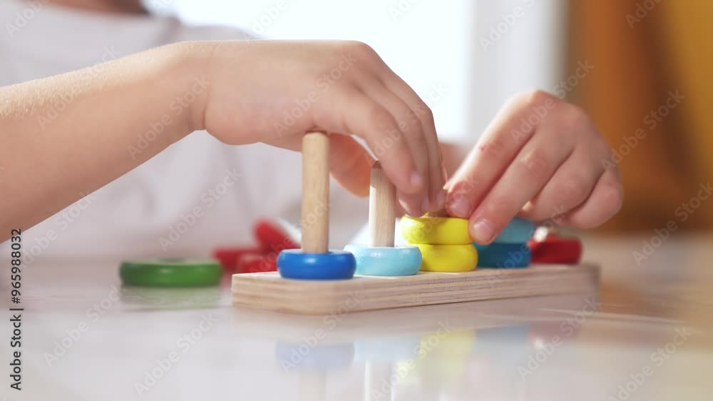 Child plays with toy r rings pyramid on table in kindergarten. Fun childhood leisure concept. The child masters fine motor skills. Child masters fine lifestyle motor skills, educational game. Child plays with toy r rings pyramid on table in kindergarten. Fun childhood leisure concept. The child masters fine motor skills. Child masters fine lifestyle motor skills, educational game.