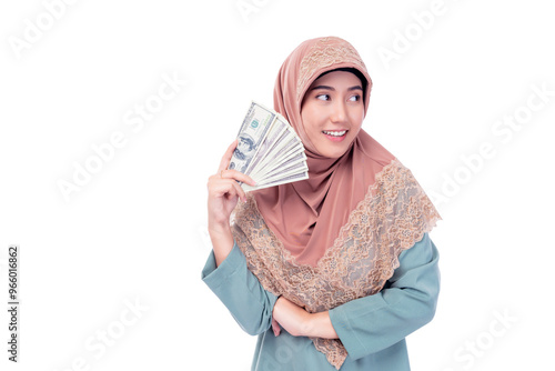 Smiling young Muslim woman in a headscarf proudly displays a fan of US dollar bills, representing financial success and empowerment. Muslim Investment Banking Financial and Economy concept