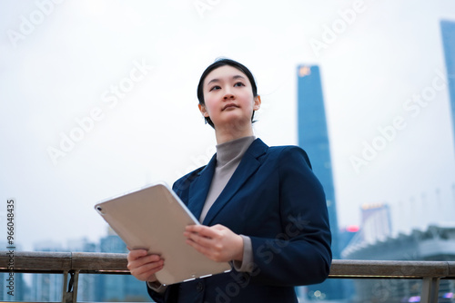 Confident Businesswoman Holding Tablet Against Urban Skyline