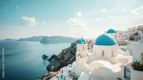 A classic view of the blue-domed Orthodox Church in Oia, Santorini, with the whitewashed village and turquoise waters of the Aegean Sea stretching out below