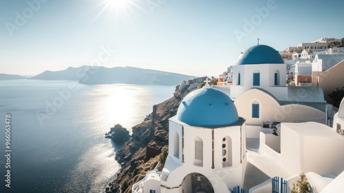 A high-angle view of the Orthodox Church in Oia, Santorini, with its blue dome shining in the sunlight, and the village and sea extending into the horizon