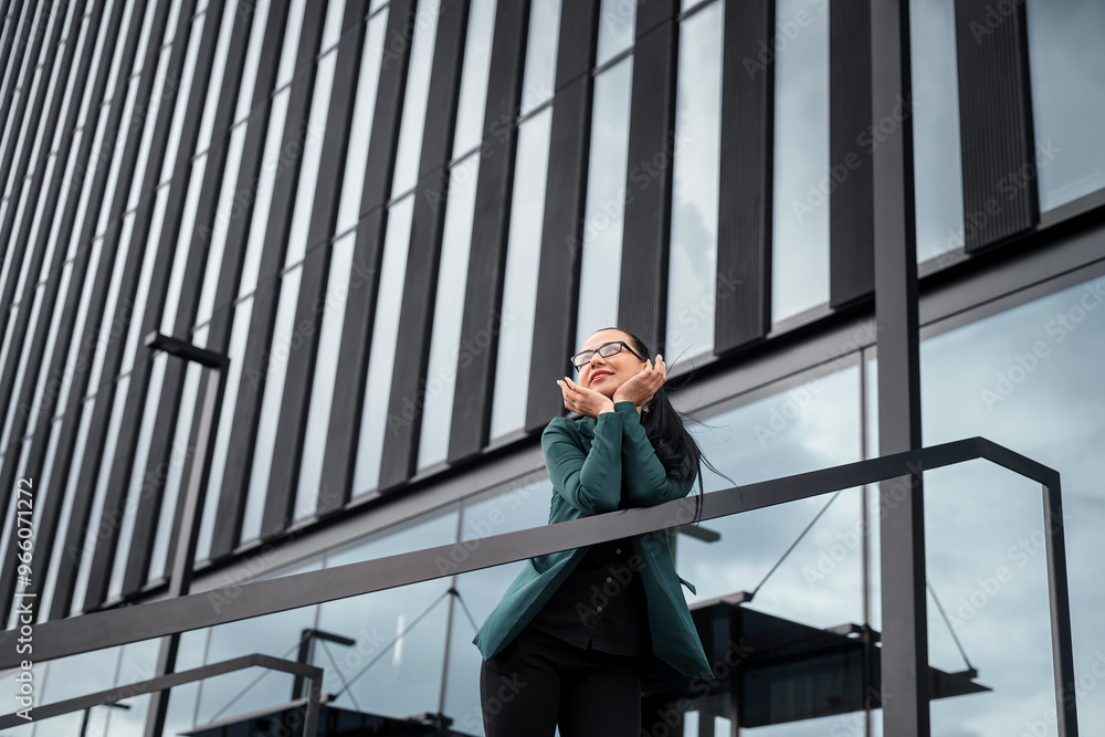 Portrait of caucasian pretty business lady in green suit standing on modern glass building Portrait of caucasian pretty business lady in green suit standing on modern glass building