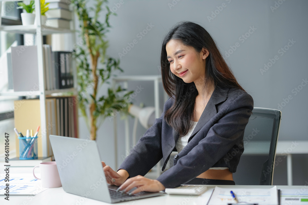 Young businesswoman smiling and working on laptop in office Young businesswoman smiling and working on laptop in office