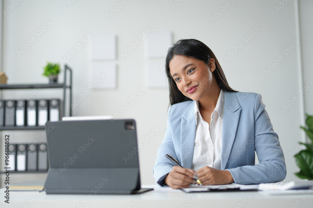 Asian businesswoman working on tablet and taking notes Asian businesswoman working on tablet and taking notes