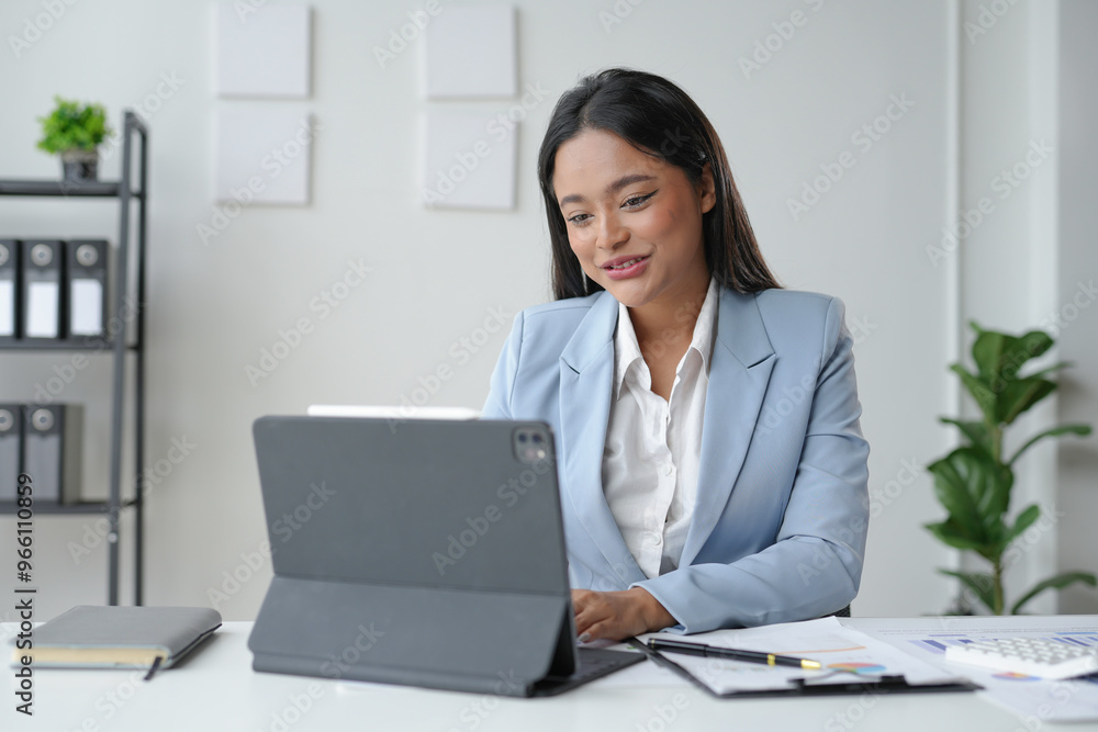 Businesswoman smiling while working on tablet at office desk Businesswoman smiling while working on tablet at office desk