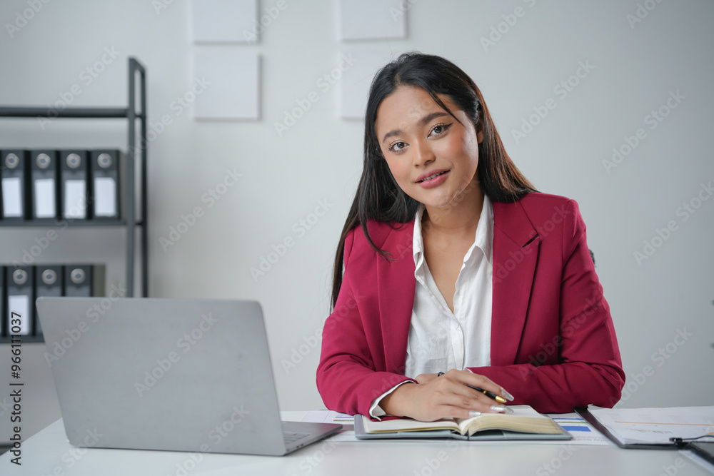 Young asian businesswoman smiling while working at her desk Young asian businesswoman smiling while working at her desk
