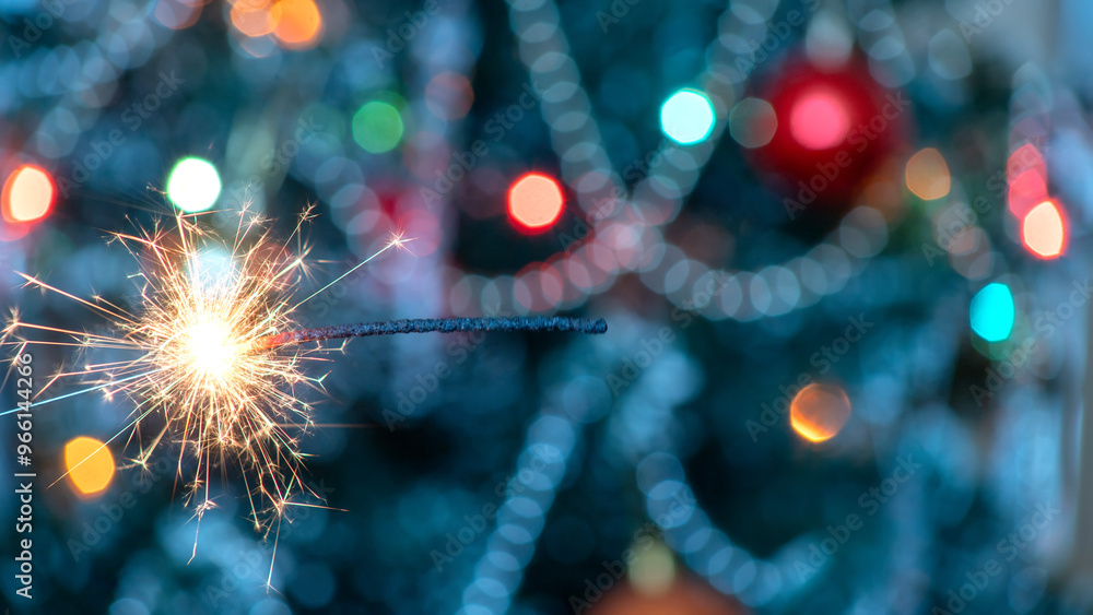 Obraz premium Close up sparkler on blurred Christmas tree background. Postcard.