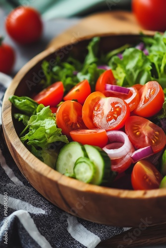 A vibrant garden salad features tomatoes, cucumbers, red onions, and leafy greens in a wooden bowl on a table setting.