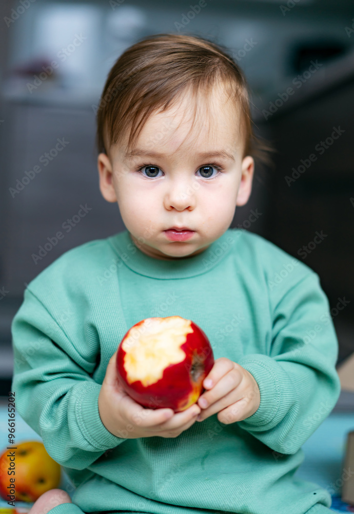 Child enjoying a fresh apple while sitting in a cozy indoor space. A young child holds a partially eaten apple, showcasing curiosity and delight Child enjoying a fresh apple while sitting in a cozy indoor space. A young child holds a partially eaten apple, showcasing curiosity and delight