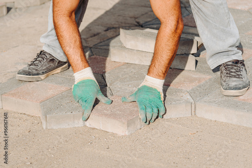 man worker in gloves lays asphalt tiles in sunny summer day, city improvement, city accomplishment concept