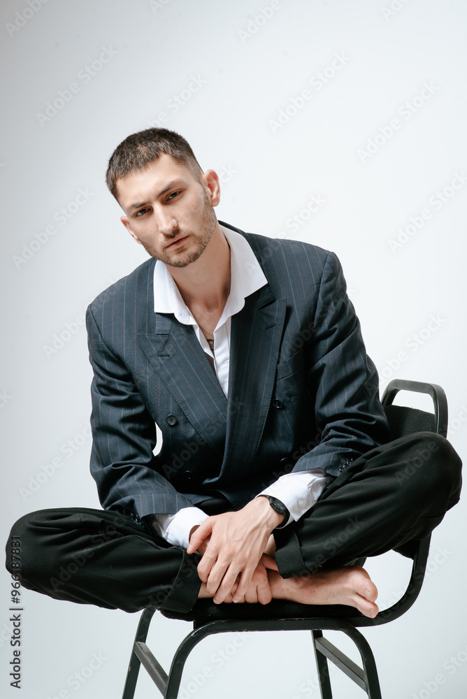 Handsome man, fashion model sits on chair barefoot