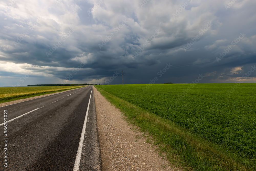 narrow rural paved road before a thunderstorm narrow rural paved road before a thunderstorm