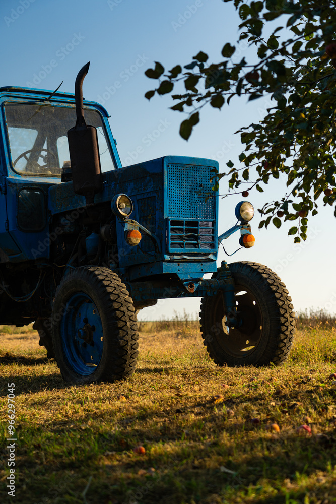 A blue, old tractor with a trailer stands near a field in the village. Morning A blue, old tractor with a trailer stands near a field in the village. Morning