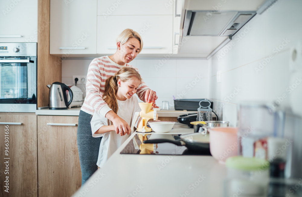 Mother and daughter enjoy warm time together in modern kitchen preparing meal. Daughter smiles warmly as they grindering using Meat grinder. Perfect for illustrating family bonding and domestic life Mother and daughter enjoy warm time together in modern kitchen preparing meal. Daughter smiles warmly as they grindering using Meat grinder. Perfect for illustrating family bonding and domestic life