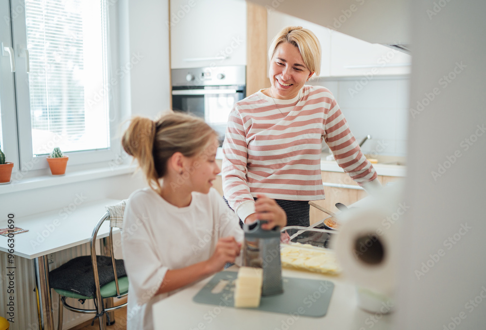 Mother and daughter enjoy warm time together in modern kitchen preparing meal. Daughter smiles warmly as they share this cooking experience. Perfect for illustrating family bonding and domestic life Mother and daughter enjoy warm time together in modern kitchen preparing meal. Daughter smiles warmly as they share this cooking experience. Perfect for illustrating family bonding and domestic life