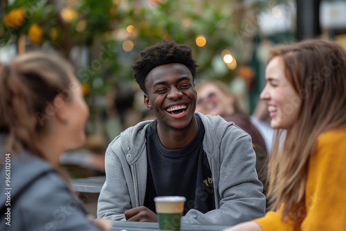 A group of people are sitting at a table, laughing and smiling. One of the people is wearing a shirt with the letters YV on it