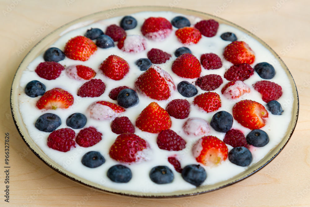 In a plate with whipped cream, strawberries, raspberries and blueberries