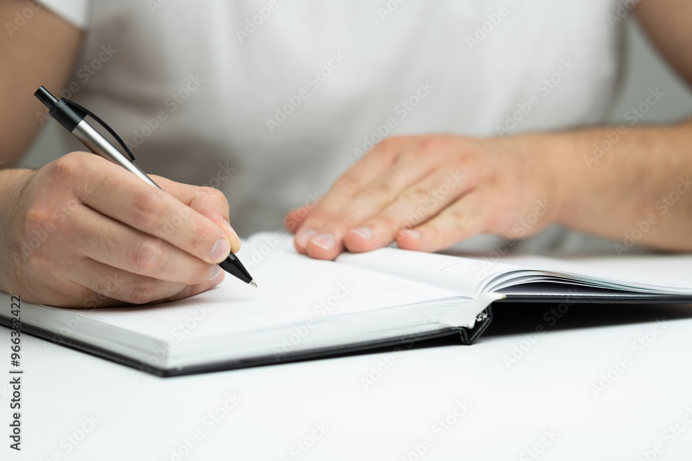 Male hand writing in notebook close up Male hand writing in notebook close up