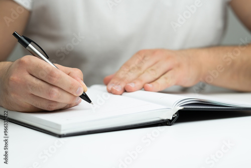 Male hand writing in notebook close up