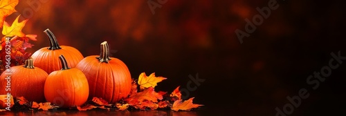 Four pumpkins arranged in a semi-circle with autumn leaves surrounding them, symbolizing the harvest, abundance, gratitude, and the beauty of fall. The pumpkins are ripe and orange, with stems and lea photo