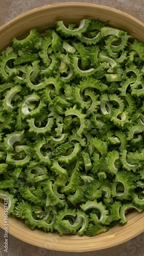 Bitter melon chunks prepared to cook or fry on a bamboo tray.  Table spin. Vertical video.