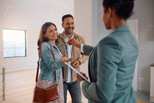 Happy couple receiving keys of their new house from real estate agent. photo