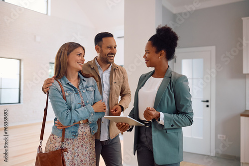 Принти на полотні Happy couple and real estate agent using digital tablet during open house day