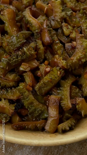 Close-up view of stir fried bitter melon in bowl. Vertical video. photo