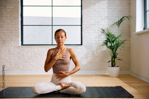 Calm woman using Pranayama breathing technique while practicing Yoga.