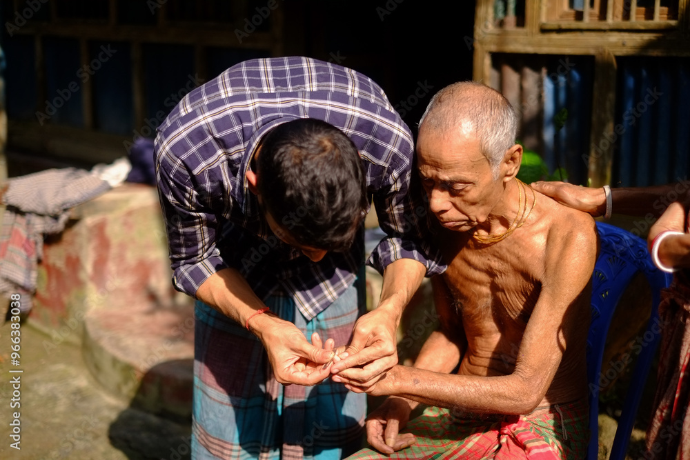 Obraz premium South asian rural son cutting his ill father’s nails 