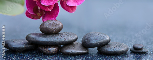 Spa stones and red orchid flowers on the gray table background.