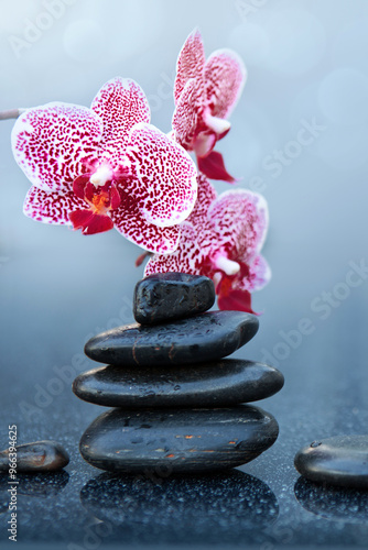 Spa stones and pink orchid flowers on the gray table background.