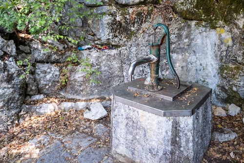 Old hand water pump in rocky forest setting photo