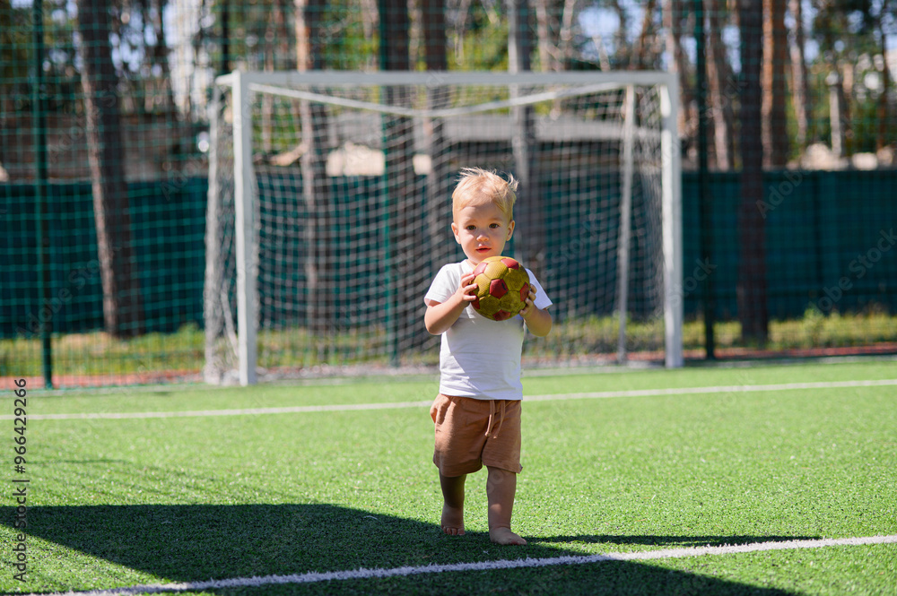 2 year old boy playing with a ball on a football field 2 year old boy playing with a ball on a football field