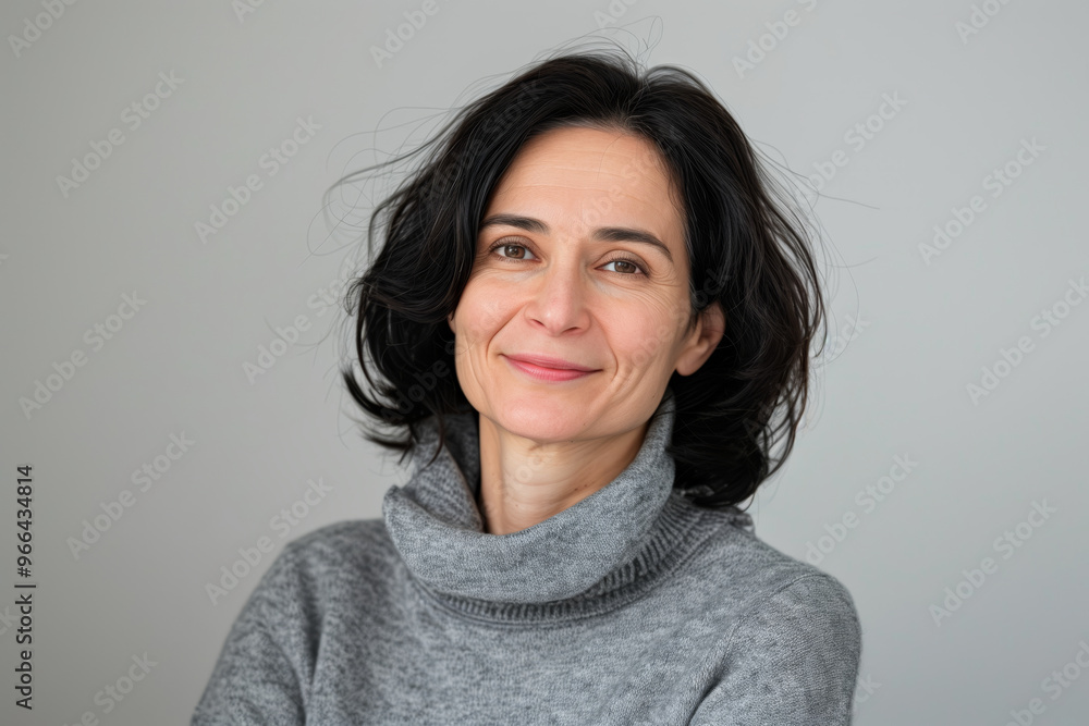 Mature woman with a gray sweater and a ponytail is smiling Mature woman with a gray sweater and a ponytail is smiling