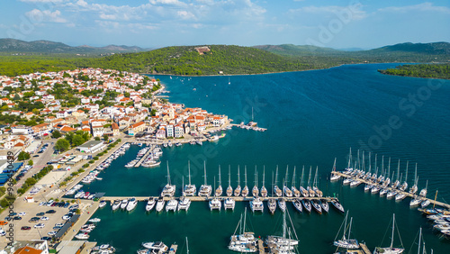 An aerial view of Pirovac Marina in Croatia, showcasing a stunning collection of yachts docked along the beautiful Adriatic coastline. The marina, surrounded by crystal-clear waters and picturesque  photo